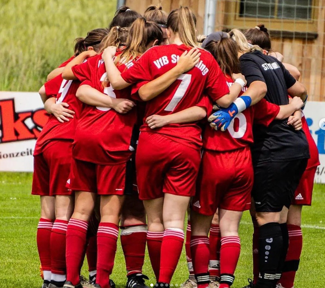 Damen-Mannschaft umarmt sich auf dem Fussballplatz